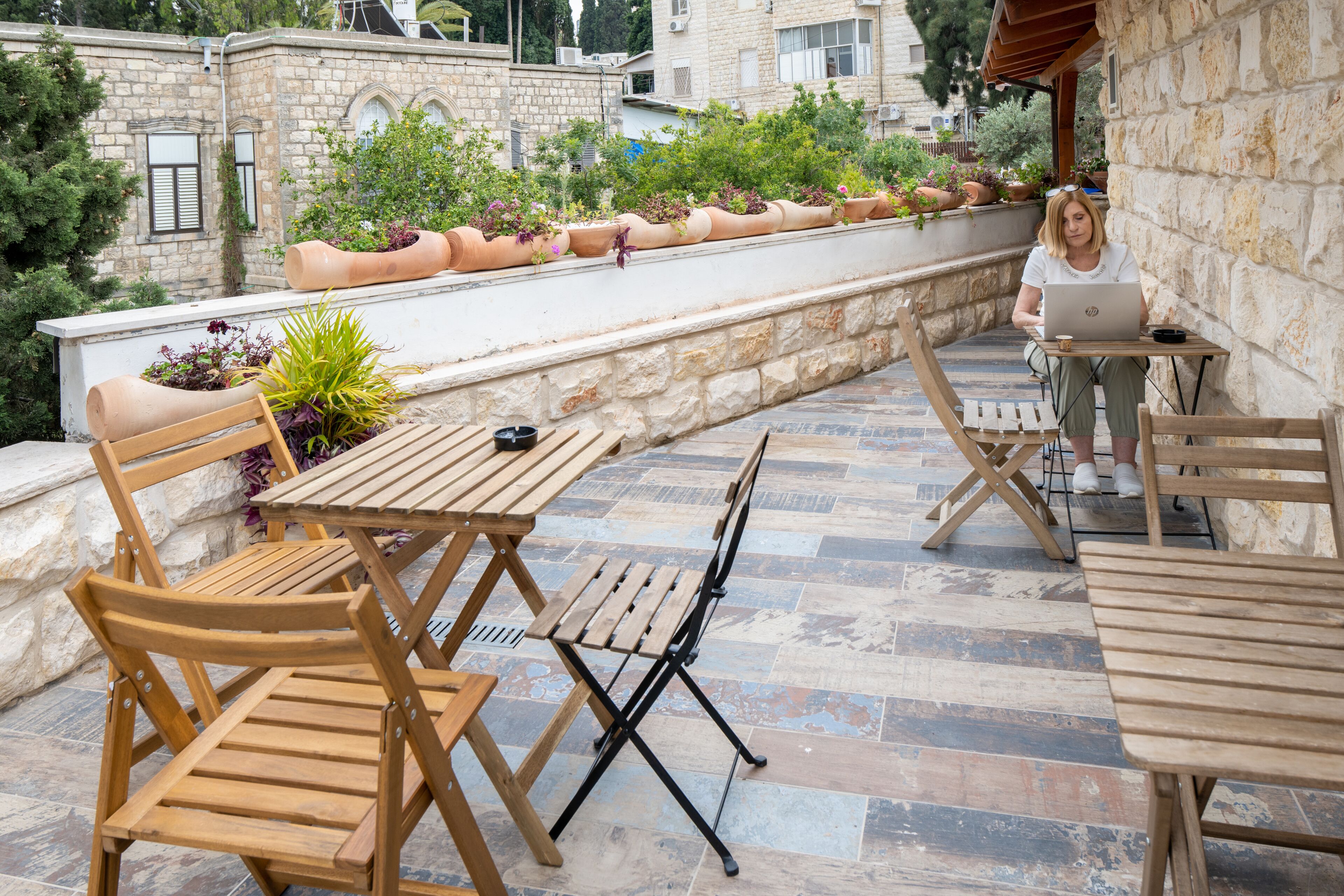Une terrasse extérieure avec des meubles en bois, un ordinateur portable et des plantes en pot.
