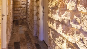 A narrow stone corridor with wooden beams on the ceiling, leading to a white door marked with the number 1. - Via Maria Boutique Suites (Haifa)