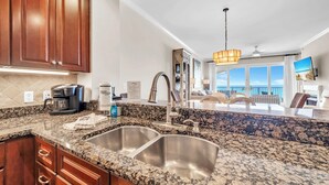 A kitchen with granite countertops, stainless steel sinks, wooden cabinets, and a coffee maker. - Adagio B-204 Beach Front - Beautiful Gulf Front Unit! (Santa Rosa Beach)
