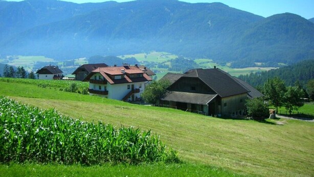 Paisaje rural con casas y montañas al fondo.