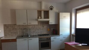 Una cocina compacta con muebles blancos, estufa a gas y horno empotrado.