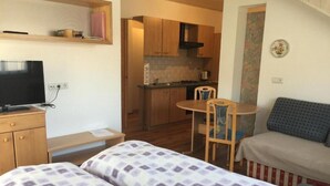 Una habitación pequeña y acogedora con cama, televisión, kitchenette y comedor.