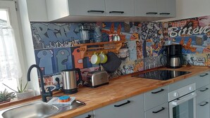 Una cocina moderna con armarios grises, encimera de madera y un salpicadero con grafitis coloridos.