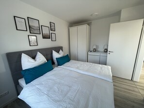 Ein Schlafzimmer mit einem Bett, zwei Nachttischen, einem Kleiderschrank und gerahmten Bildern an der Wand.