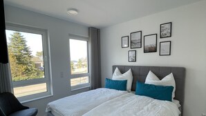 Ein modernes Schlafzimmer mit einem großen Bett, einem Sessel und einem Fenster mit Blick.