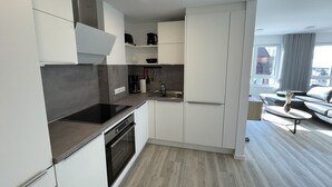 Eine moderne Küche mit weißen Schränken, einem eingebauten Backofen und einer Kaffeemaschine.