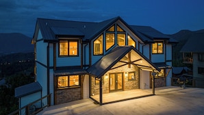 A multi-story house with a stone facade, large windows, and a covered porch. - Priceless Views, Indoor Pool Firepit Pool Table, Hot Tub, & Free Attractions! (Gatlinburg)