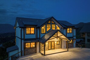 A multi-story house with a stone facade, large windows, and a covered porch. - Priceless Views, Indoor Pool Firepit Pool Table, Hot Tub, & Free Attractions! (Gatlinburg)