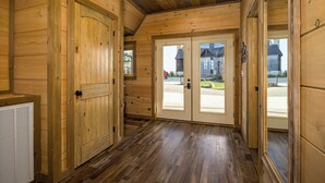 A wooden interior with a hallway leading to a double door with glass panels, a radiator, and a ceiling with exposed beams. - Priceless Views, Indoor Pool Firepit Pool Table, Hot Tub, & Free Attractions! (Gatlinburg)