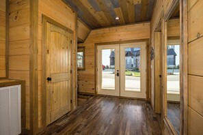 A wooden interior with a hallway leading to a double door with glass panels, a radiator, and a ceiling with exposed beams. - Priceless Views, Indoor Pool Firepit Pool Table, Hot Tub, & Free Attractions! (Gatlinburg)