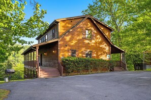 A log cabin with a porch, a mailbox, and a well-maintained lawn.