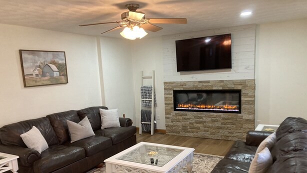 Una sala de estar con chimenea, sofás de cuero, una mesa de centro y un televisor montado en la pared.