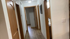 Un pasillo con suelo de madera y puertas que dan a otras habitaciones.