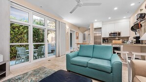 A modern kitchen with stainless steel appliances, a teal sofa, and a dining area with white furniture. - Walk to the Waves- Gorgeous Carillon Beach Bungalow (Panama City Beach)