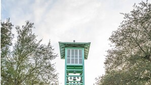 A white tower with green accents, surrounded by a well-maintained lawn and trees. - Walk to the Waves- Gorgeous Carillon Beach Bungalow (Panama City Beach)