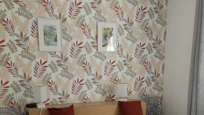 A neatly made bed with white bedding, a wooden headboard, and two red pillows. There are two framed pictures on the wall above the bed. - New comfortable house with swimming pool in Provence (Régusse)