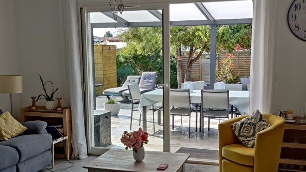 A living room with a sofa, coffee table, and a yellow armchair. There is a sliding glass door leading to an outdoor patio with a table and chairs. - New comfortable house with swimming pool in Provence (Régusse)