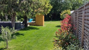 A well-maintained garden with a wooden fence, a small wooden structure, and a variety of plants. - New comfortable house with swimming pool in Provence (Régusse)