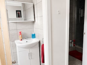 Ein Badezimmer mit Waschbecken, Spiegel und Duschbereich.