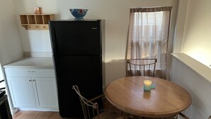 Una cocina compacta con un refrigerador negro, una mesa de madera con una vela y una silla.