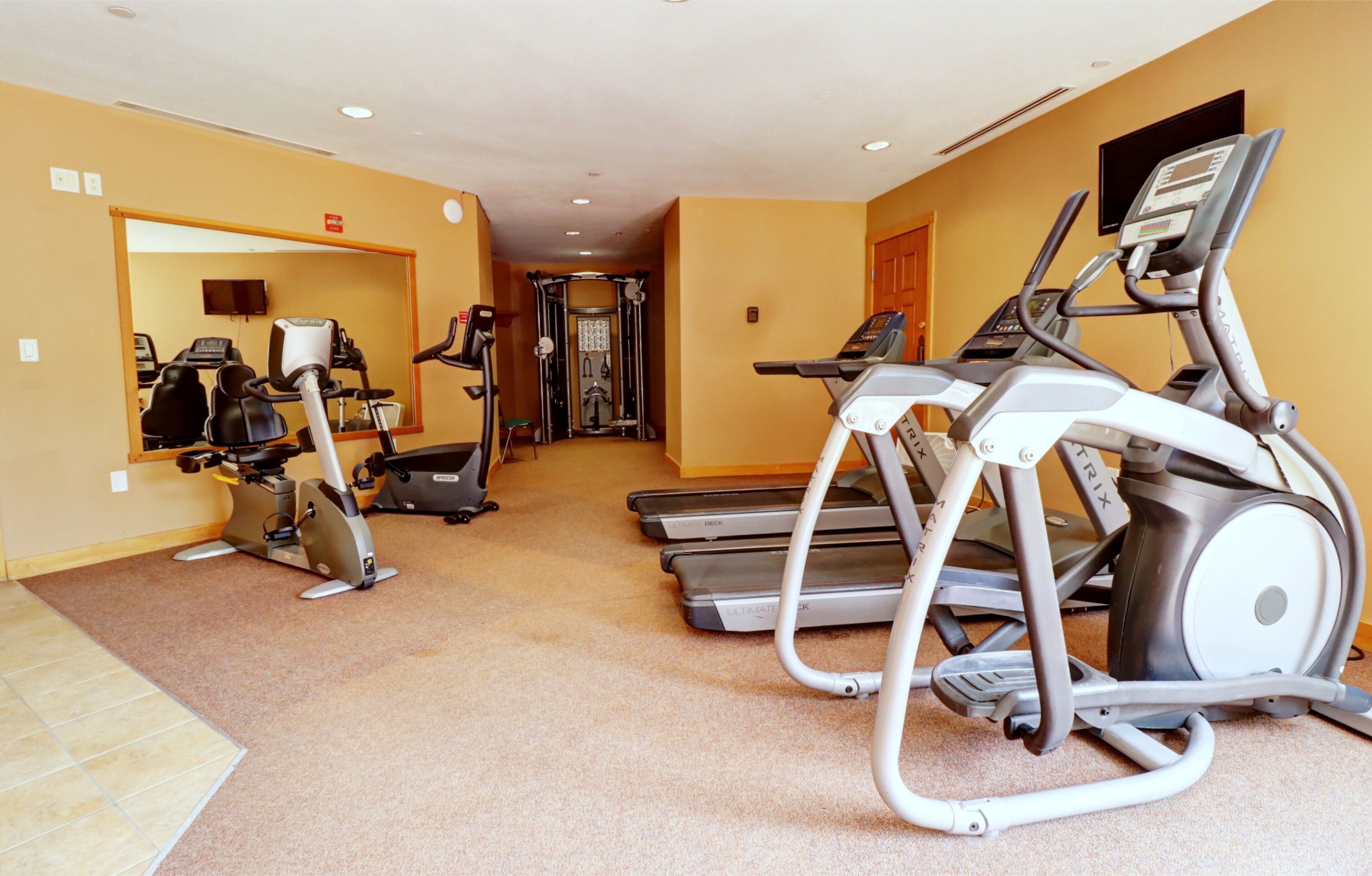 Un gimnasio con cintas de correr, bicicletas estáticas y una máquina de pesas.