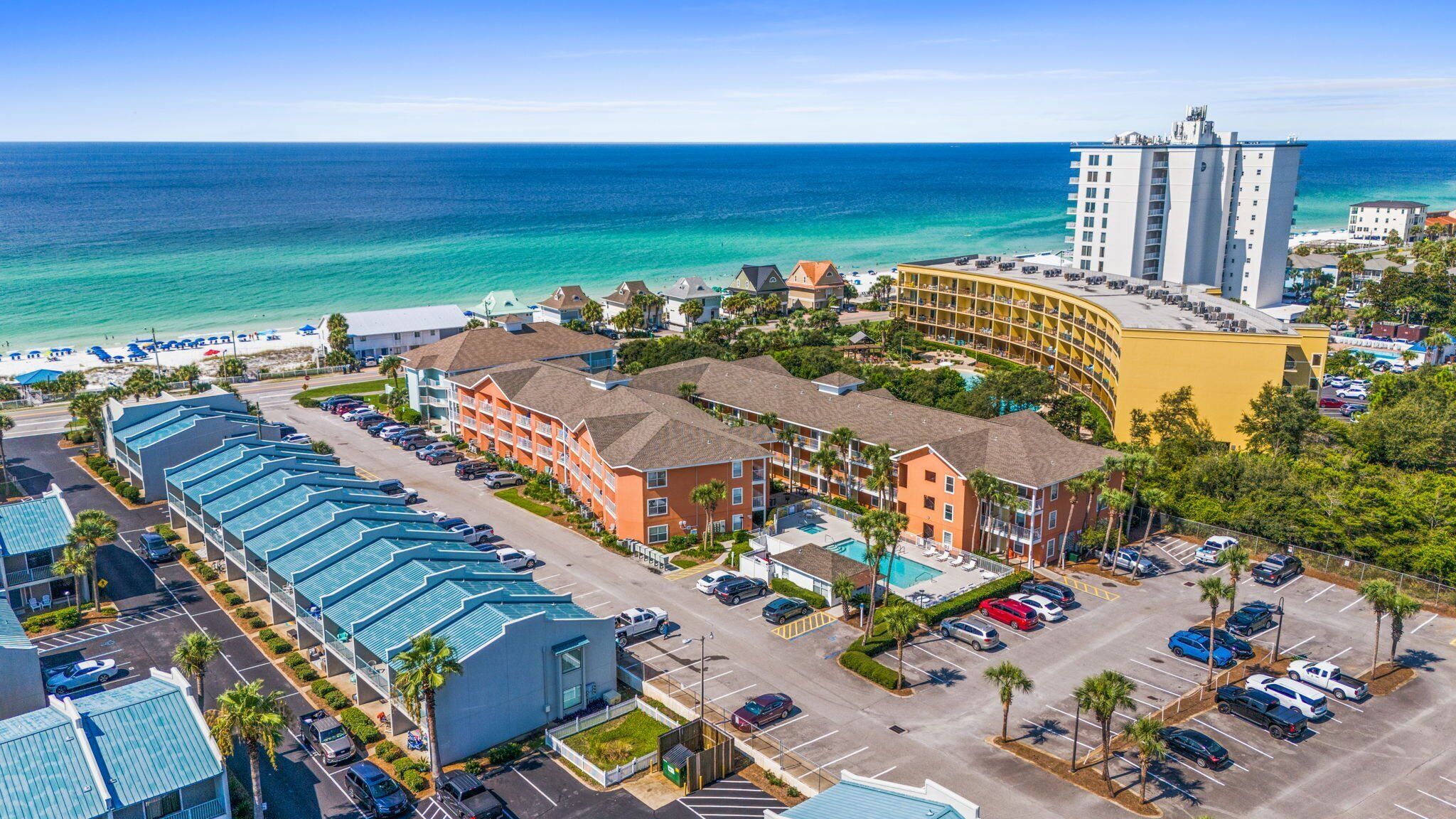 Ein Küstenhotel mit mehreren Gebäuden, einem Parkplatz und Blick auf das Meer.
