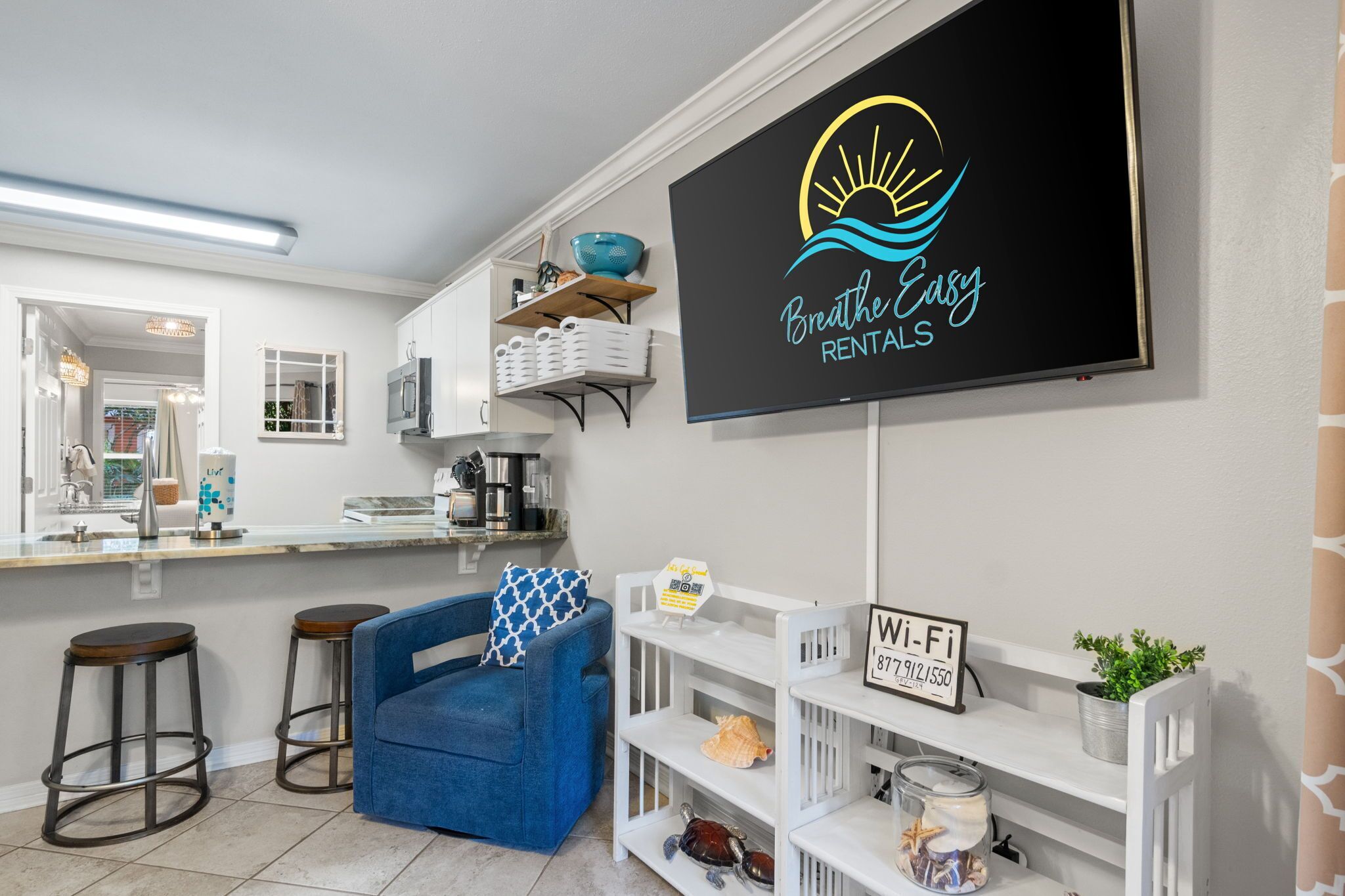 A modern kitchen with white cabinets, a blue chair, and a Wi-Fi sign.