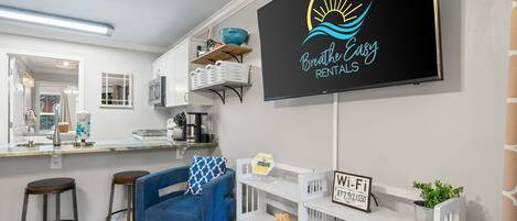 A modern kitchen with white cabinets, a blue chair, and a Wi-Fi sign.