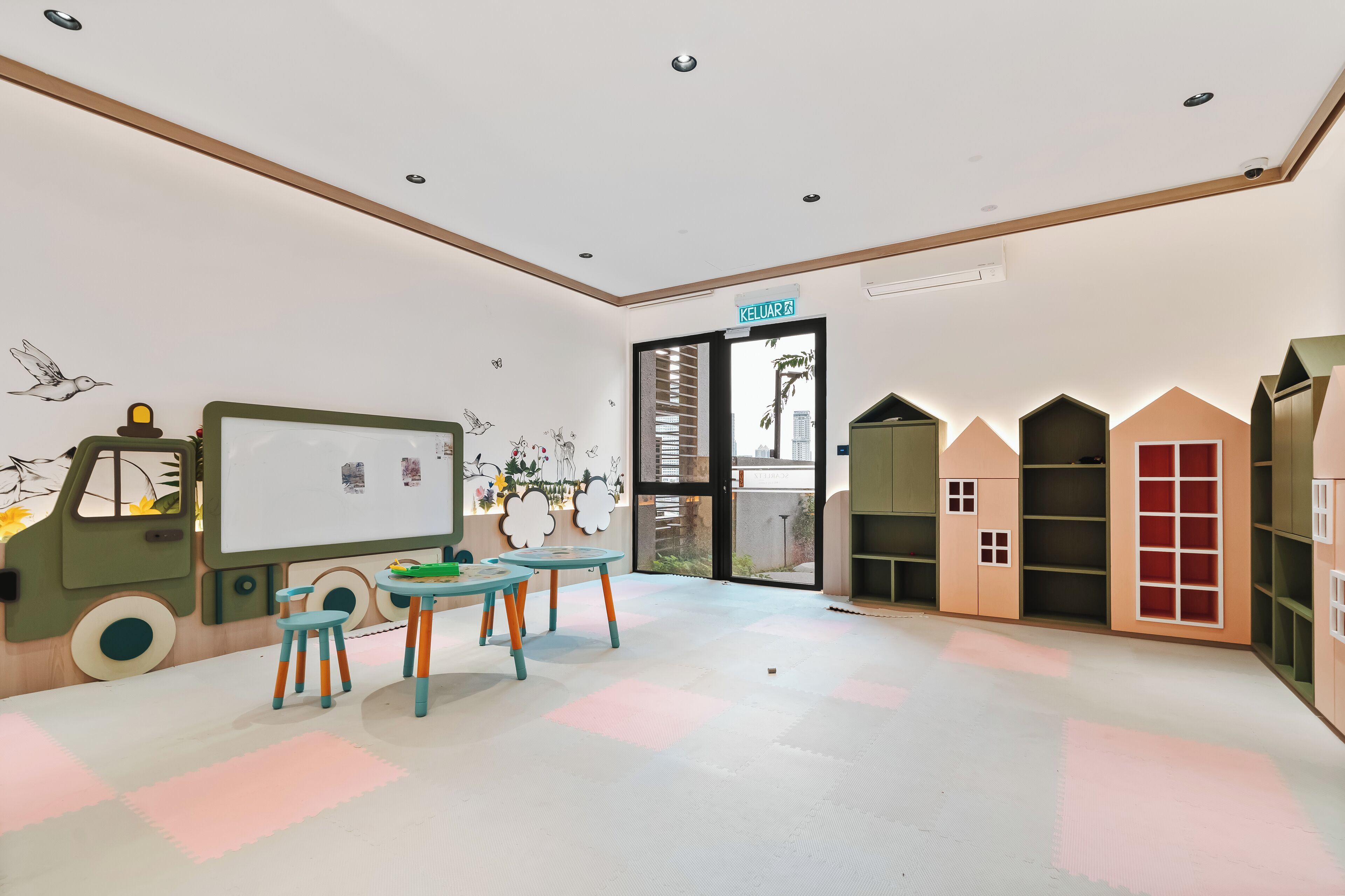 A children's playroom with a whiteboard, a toy truck, and a table with chairs.