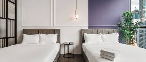 A hotel room with two beds, a small table, a wall-mounted light, and a view of the city.