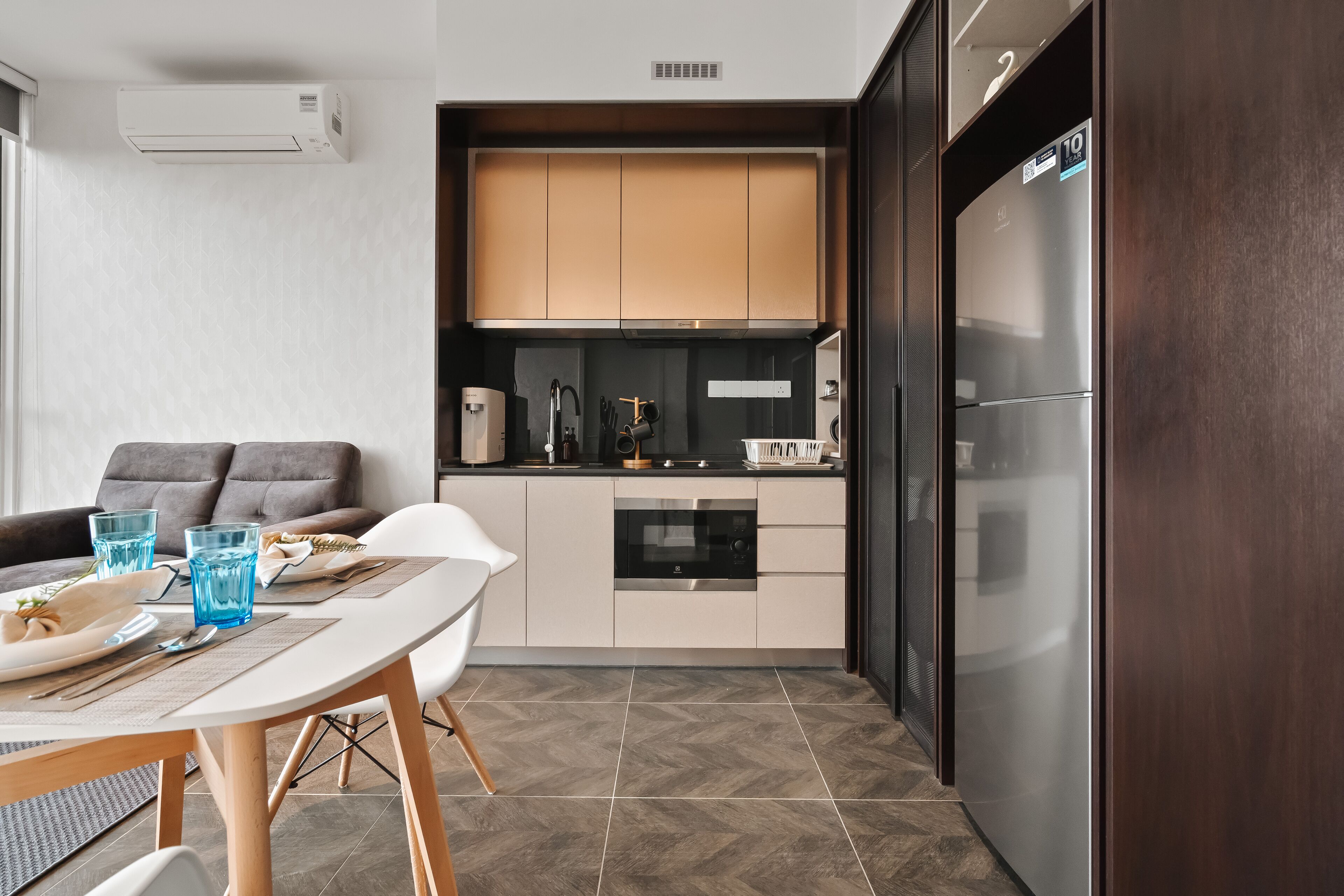 Une cuisine compacte dotée d’appareils électroménagers modernes, un coin repas avec une table et des chaises, et un canapé.