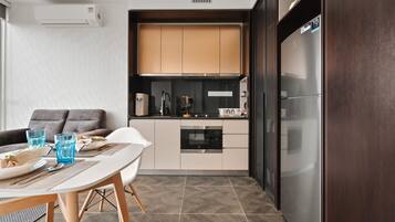 Une cuisine compacte dotée d’appareils électroménagers modernes, un coin repas avec une table et des chaises, et un canapé.