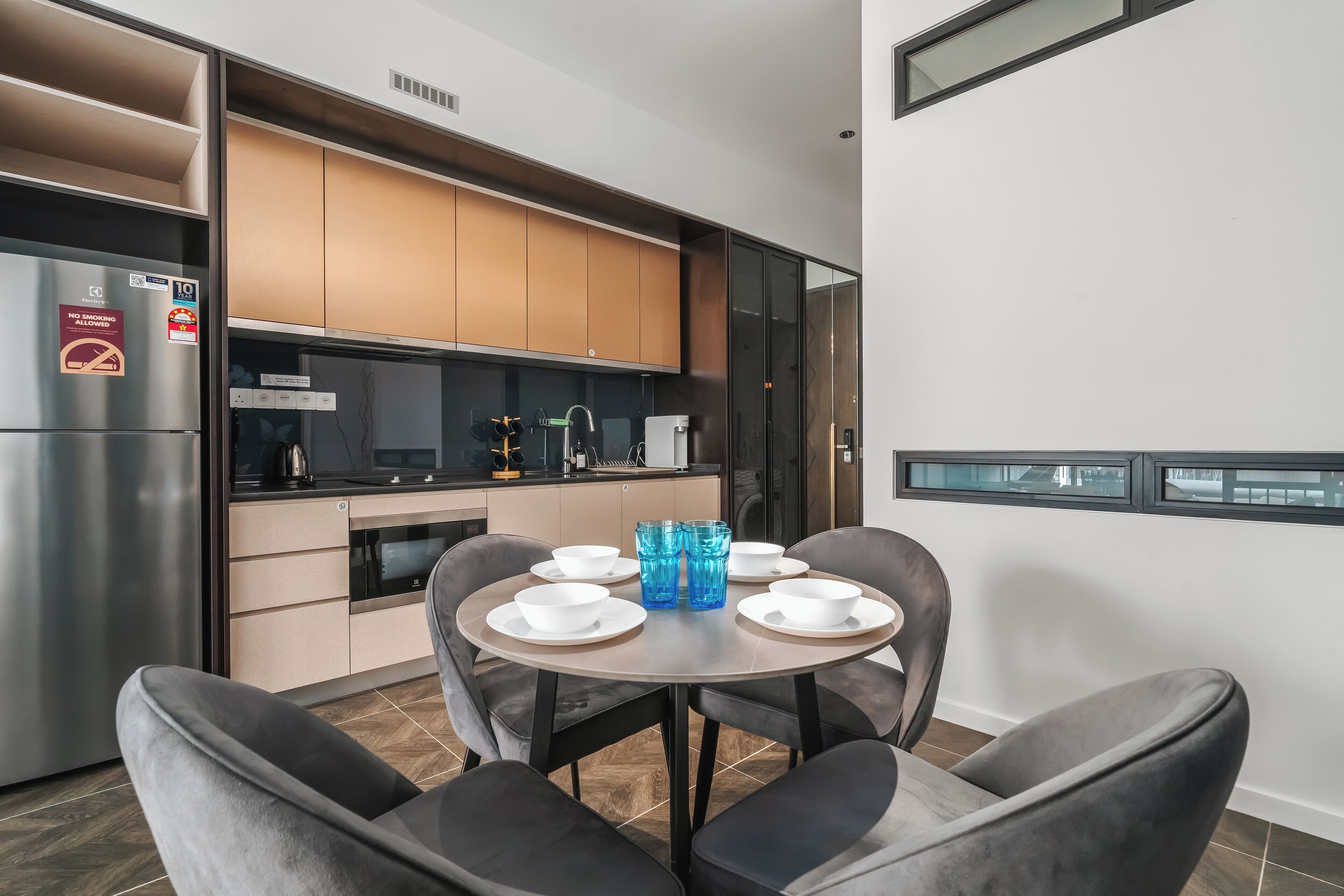 A modern kitchen with built-in appliances, a dining area with a table set for two, and a view of the street outside.