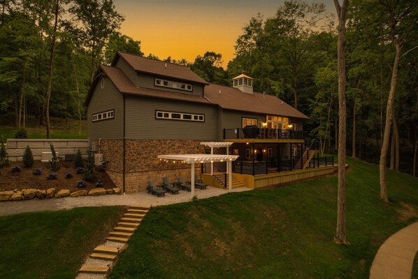 A two-story house with a stone foundation, a large deck, and a covered patio area. - Lakes, Waterfall, Basketball Court: Family Getaway 5-7 bedrooms (Dover)
