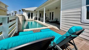 Un área de piscina con sillones de descanso y un porche cubierto.