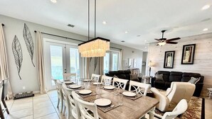 Un comedor con una mesa de madera dispuesta para seis personas, rodeada de sillas blancas.