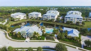 Een resort met meerdere gebouwen, een centraal zwembad en omliggend groen.