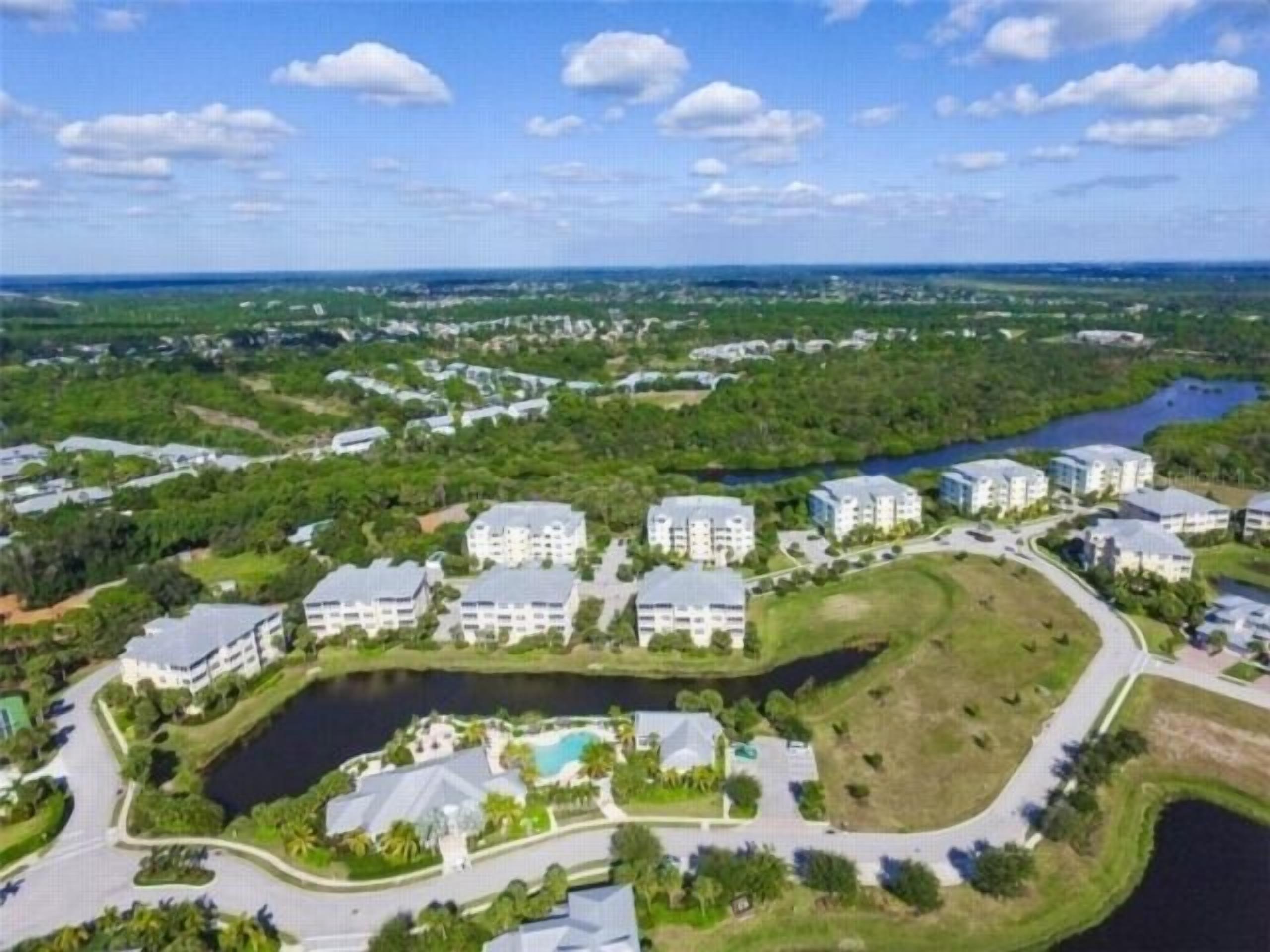 A residential area with multiple apartment buildings, a central swimming pool, and a river.