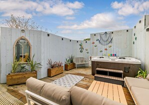 Relax in a serene outdoor space with a sofa, chair, and hot tub.