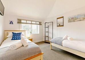Cozy retreat with two beds, a window, and a decorative painting.