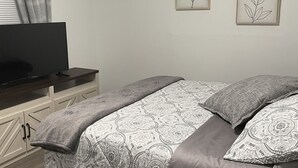 Una camera da letto con un letto, una televisione, una scrivania e due quadri appesi al muro.