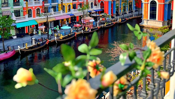 A colorful waterfront area with buildings, a canal, and boats. - HANZ VeniceRiver Sunset Grand World (Phu Quoc)