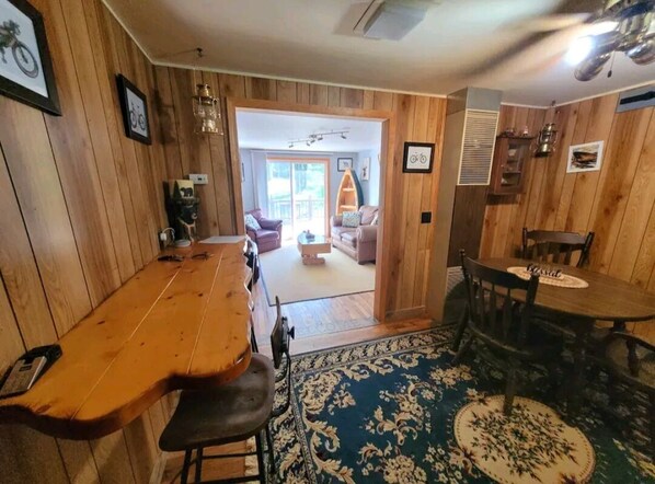 Un interior de madera con una mesa de comedor, sillas y una alfombra estampada.