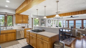 Une cuisine spacieuse avec des meubles en bois, un îlot central et des luminaires suspendus.