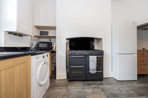 A compact kitchen with a washing machine, a stove, a microwave, and a refrigerator.