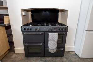 Una cocina con estufa negra, horno y refrigerador blanco.