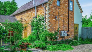 A brick building with a sloped roof, a wooden door, and a window.