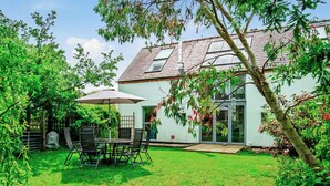 A house with a patio, a covered table and chairs, and a lawn.