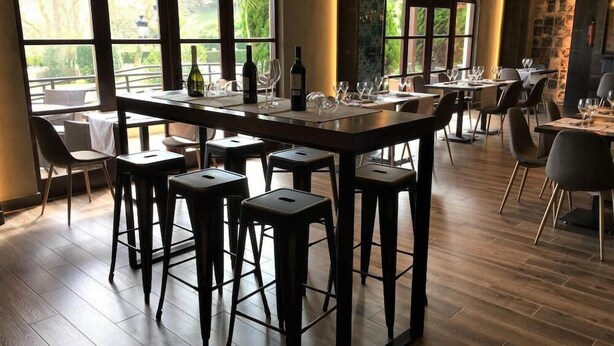 A restaurant with a bar area, high tables, and chairs. - Hotel Comillas (Comillas)