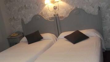 Una cama doble con dos almohadas, una mesita de noche con lámpara y una pared con textura.